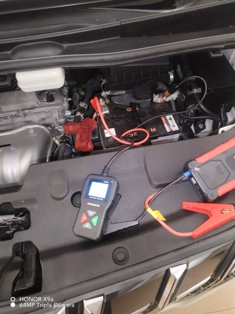 Battery tester and jump starter clamped onto a car battery