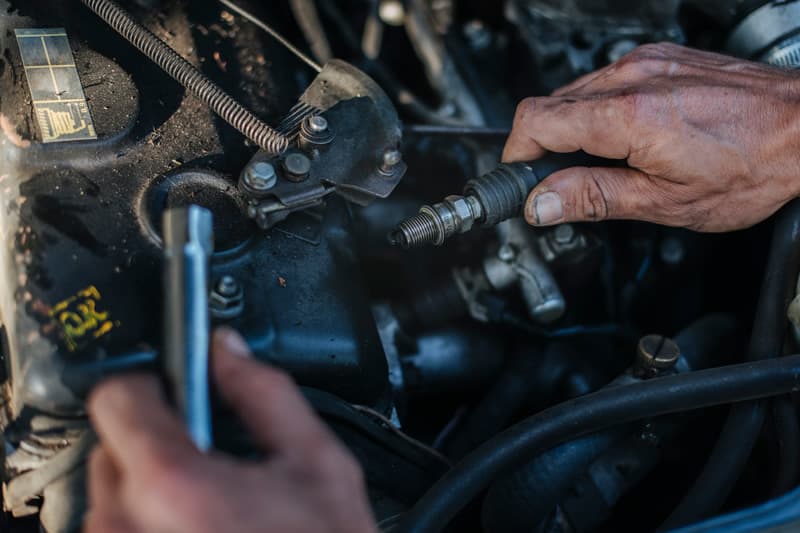Mechanic hands removing a spark plug at an outdoor job